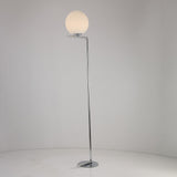 The Vetra 1 Light Opal Glass Floor Lamp - Grey features a slim chrome stand, opal glass sphere top, and glossy circular base, adding soft ambient lighting to any light-colored space with its modern design.