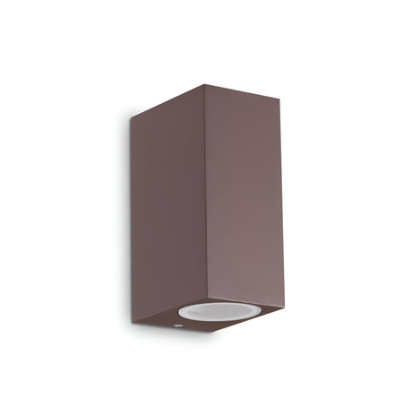 The Aethera Outdoor 2 Light Wall Light in brown is a sleek and minimalist rectangular fixture with an IP44 rating. Designed to illuminate exterior spaces, it features a flat surface with a single bulb socket and can be mounted vertically against a plain white background for optimal lighting. Additionally, the fixture is dimmable for customizable illumination.