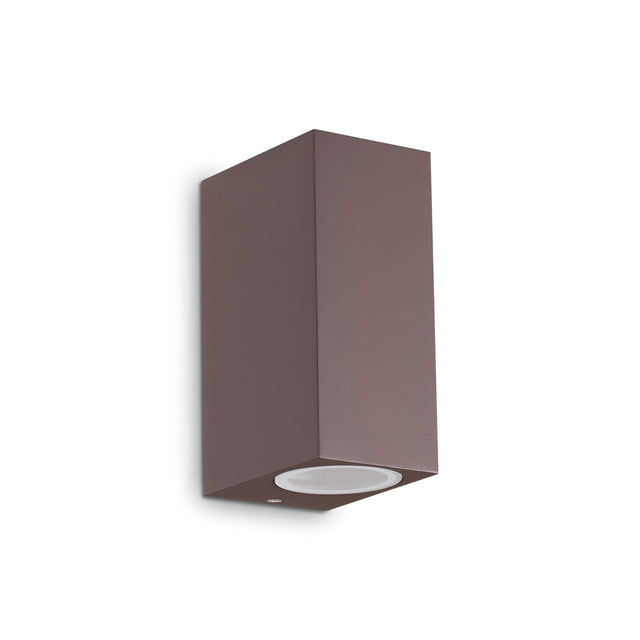 The Aethera Outdoor 2 Light Wall Light in brown is a sleek and minimalist rectangular fixture with an IP44 rating. Designed to illuminate exterior spaces, it features a flat surface with a single bulb socket and can be mounted vertically against a plain white background for optimal lighting. Additionally, the fixture is dimmable for customizable illumination.