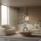 A modern living room with beige walls, cream sofas, a round wooden coffee table, vases, a potted plant, and the Cintura LED Small Alabaster Single Pendant Light in soft white & brown elegantly illuminating the space.