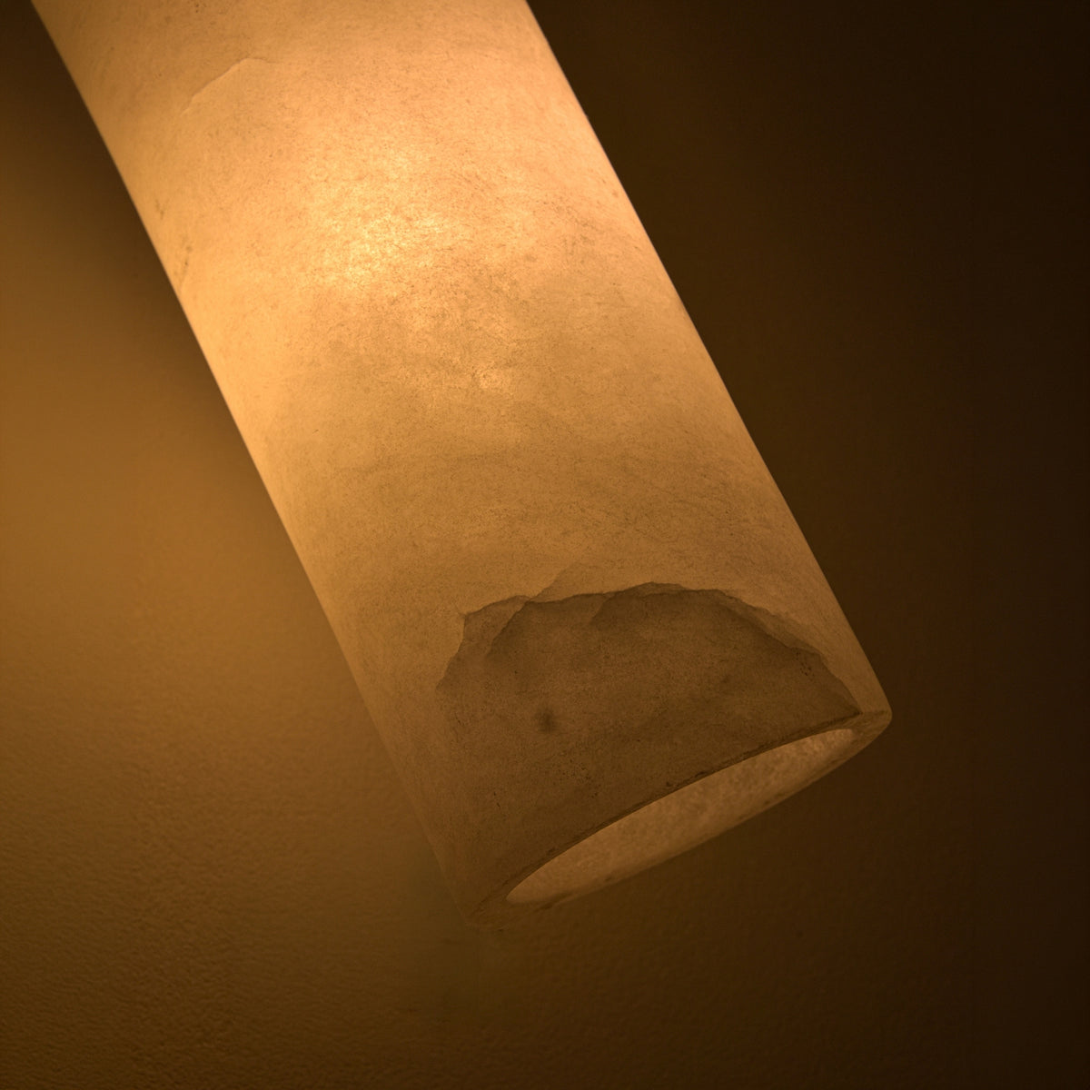 Velmora Slim Cylindrical Alabaster Pendant Light in soft white stone, close-up of the tall tube shade glowing warmly from within, showing natural texture and an open lower edge.