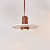 Torvane 1 Light Travertine Disc Pendant Light with a light beige stone disc and walnut brown wooden column, glowing centre light, on a plain white background.