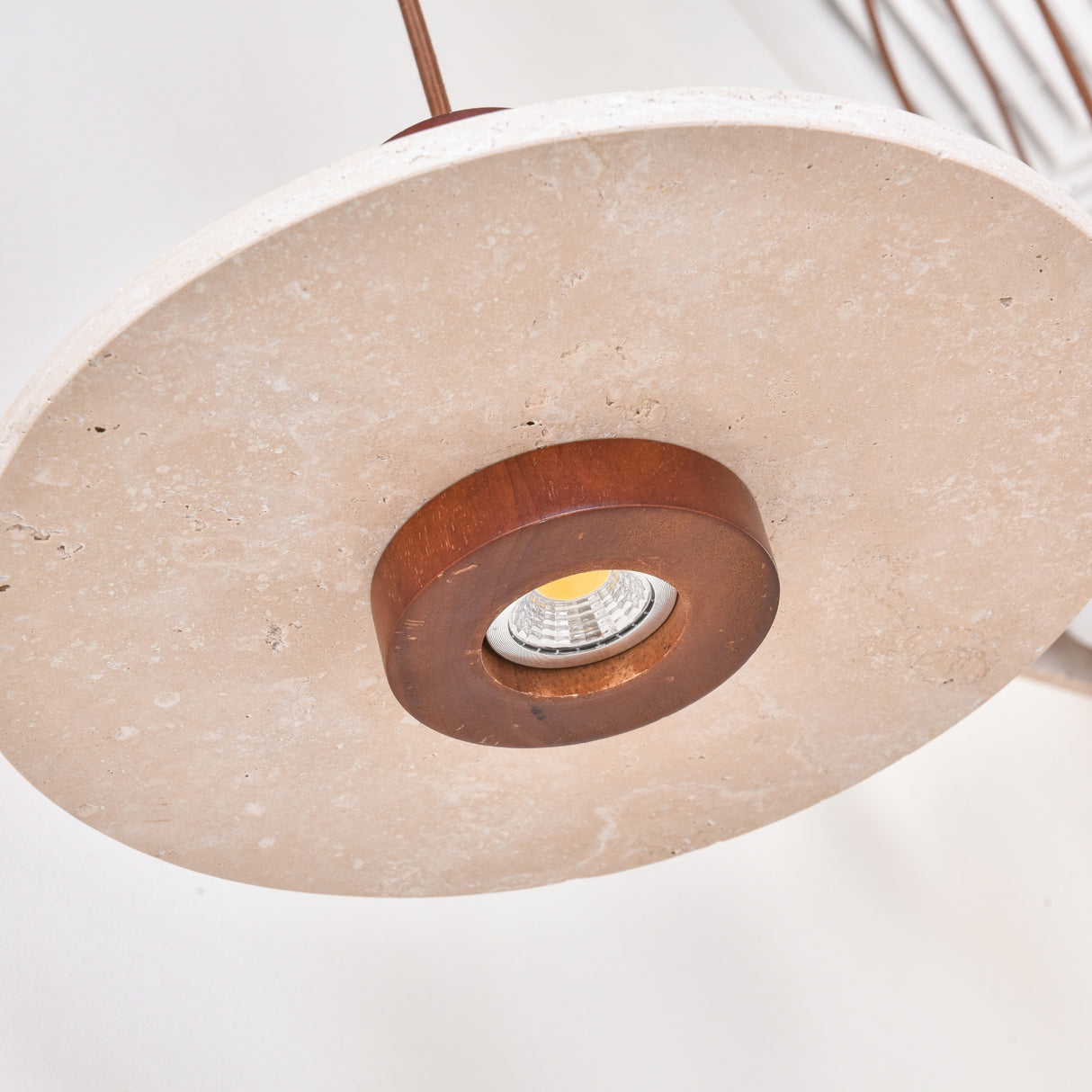 Torvane 1 Light Travertine Disc Pendant Light in light beige stone with a walnut brown wooden column, showing the recessed downlight at the disc's centre.