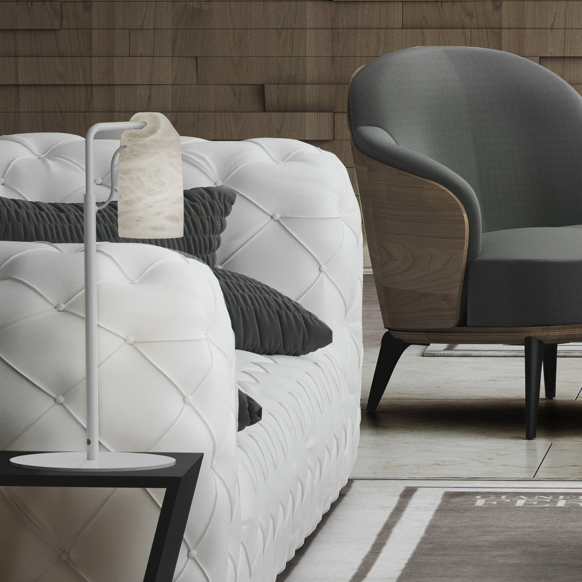 Paros Alabaster Table Lamp in white, with a slim iron stem and hanging alabaster shade, shown beside a tufted white sofa and grey armchair in a living room setting.