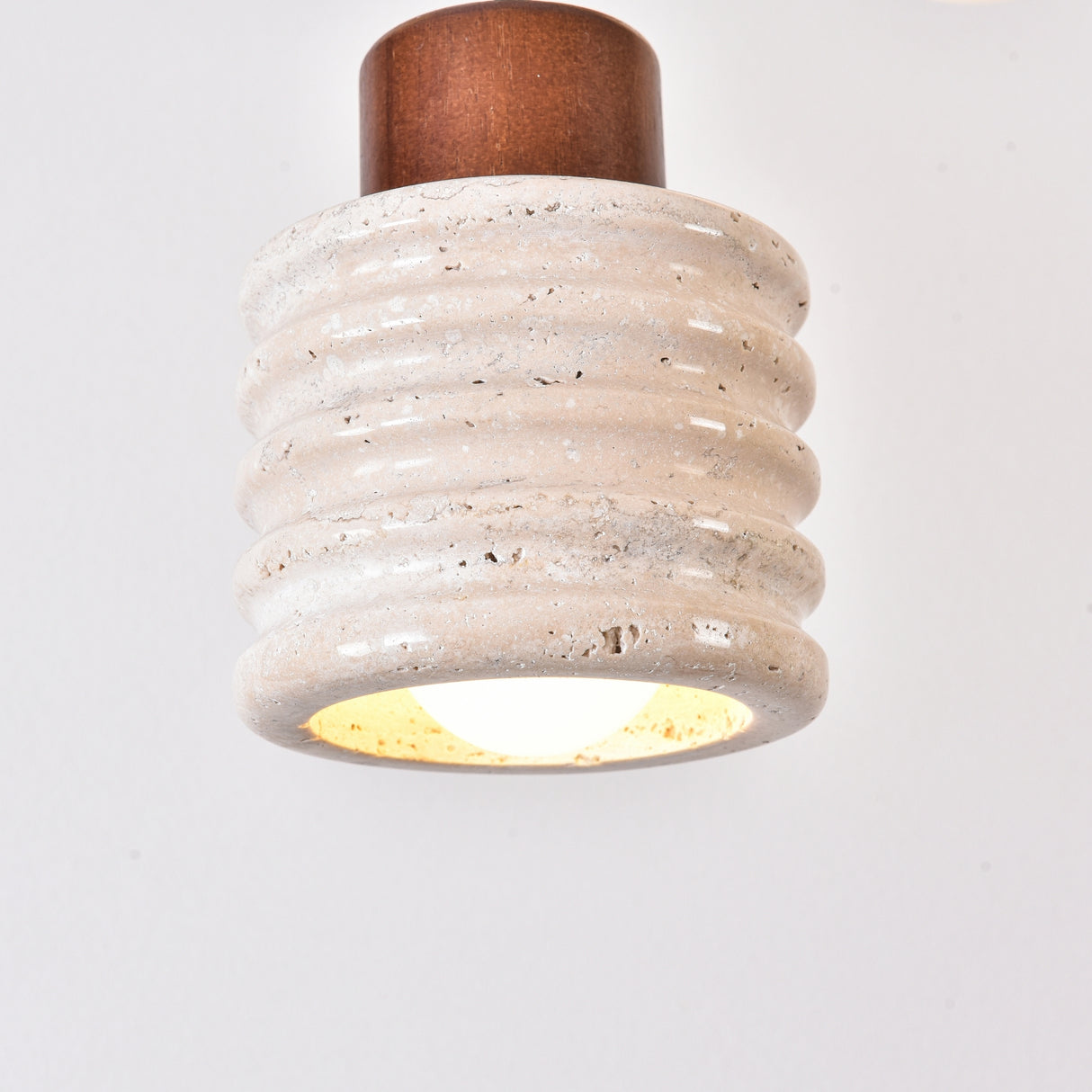 Rivano Ribbed Travertine Pendant Light with ribbed light beige stone drum, walnut wood top, and glowing E27 bulb, shown against a plain white background.