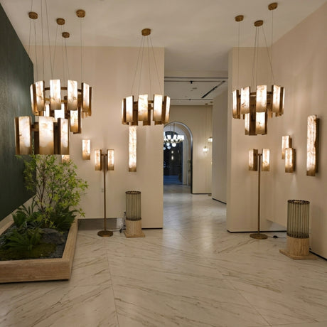 Caelith 20-light 2-tier panel alabaster chandelier in brushed brass, shown among matching pendants and wall lights in a marble-floored hallway.