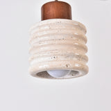 Rivano Ribbed Travertine Pendant Light in light beige with a walnut wood top, showing the ribbed stone drum and exposed E27 bulb against a plain white background.