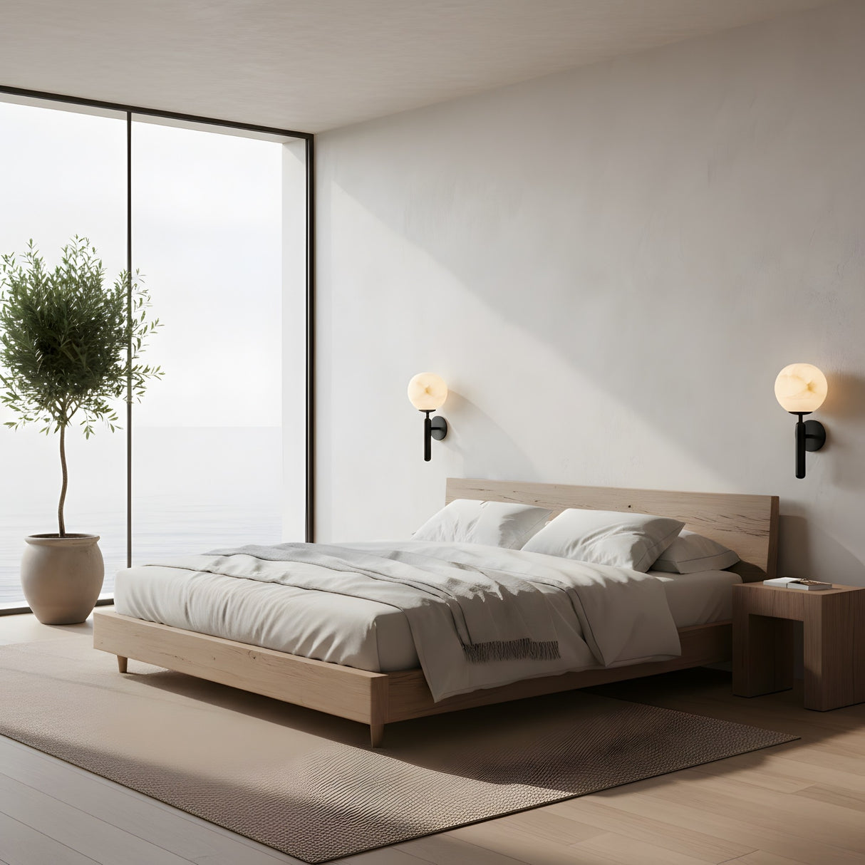 Minimalist bedroom with a low wooden bed, white bedding, two Etoile 1 Light Sphere Alabaster Wall Lights in soft white & matte black, a small wooden bedside table, large potted plant, and floor-to-ceiling windows with serene water views.