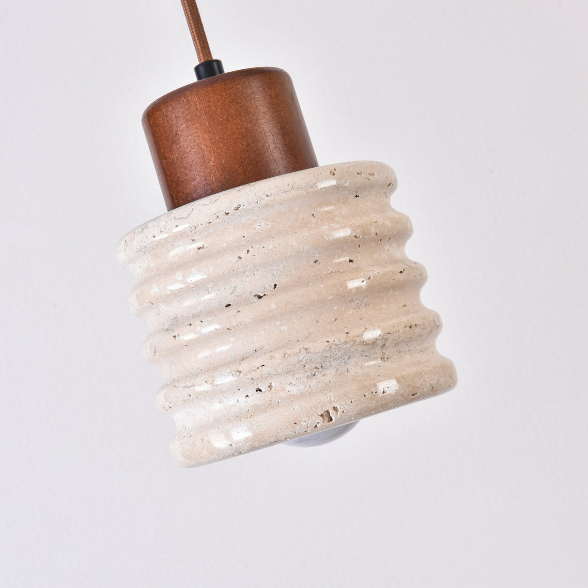 Rivano Ribbed Travertine Pendant Light with a ribbed light beige stone drum, walnut wood top cap, and fabric cord, shown against a plain white background.