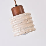 Rivano Ribbed Travertine Pendant Light with a ribbed light beige stone drum, walnut wood top cap, and fabric cord, shown against a plain white background.