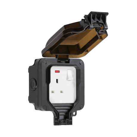 The IP66 13A 1 Gang DP Switched Socket Neon is a black weatherproof outdoor power socket with one outlet, equipped with an open, transparent lid. This socket features a switch and a red indicator light on the left, and its cover is hinged at the top.