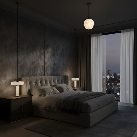 A modern bedroom at night features a large bed, two bedside tables, and the Olivaro 1 Light Petal Form Alabaster Single Pendant Light in Soft White & Brushed Brass casting a soft glow. Dark textured walls, tall curtains, and city views complete the cozy setting.