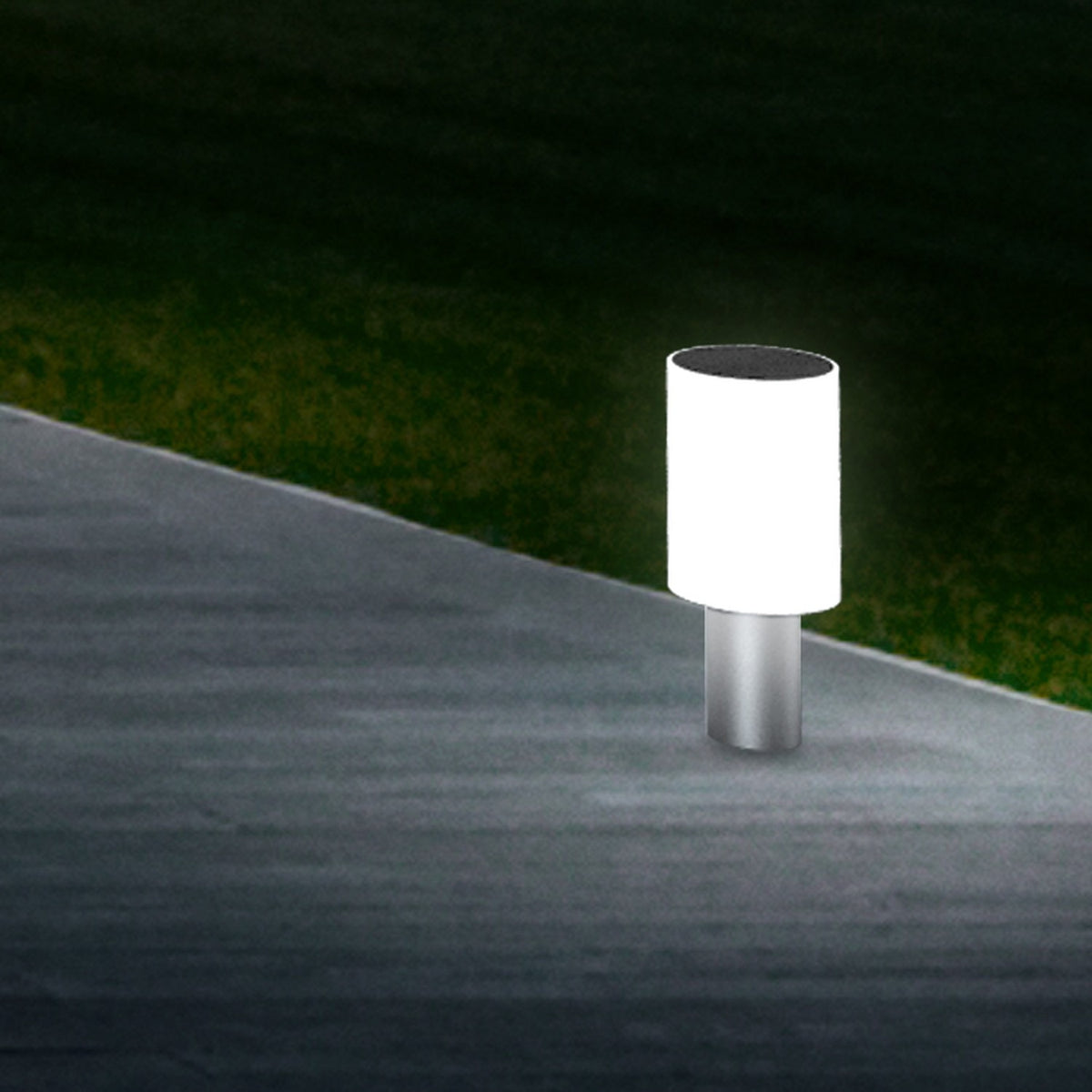 Tiny Round Pillar Light IP45 in satin nickel, illuminated white cylindrical shade on a slim metal stem, shown outdoors on a paved path edge at night.
