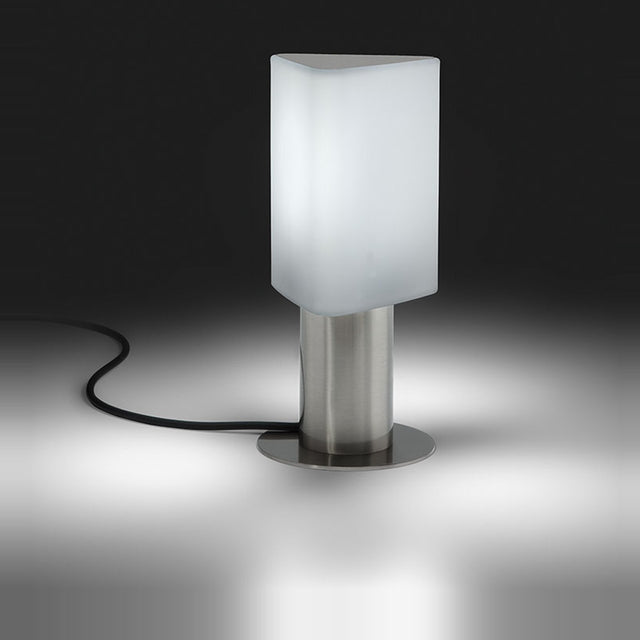Tiny Triangle Table Lamp in satin nickel with a frosted triangular plastic shade, lit from within, on a cylindrical metal base with round foot, shown against a dark background.