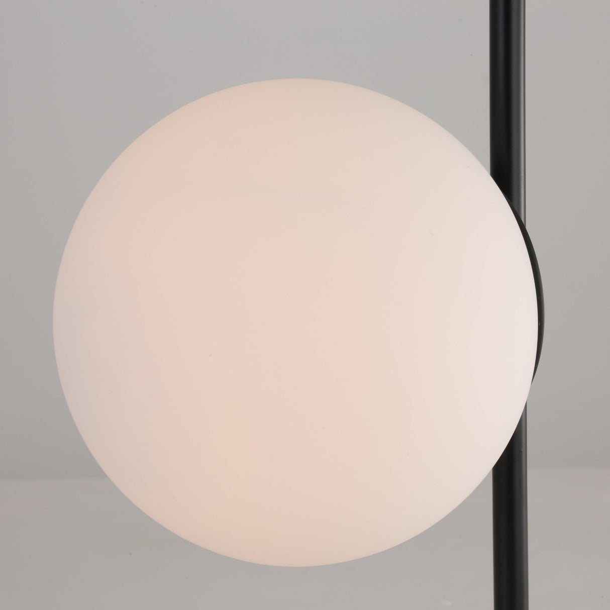 The Vetra 1 Light Opal Glass Table Lamp - Black features a round, white frosted opal glass globe on a sleek vertical black metal pole, set against a light gray background.