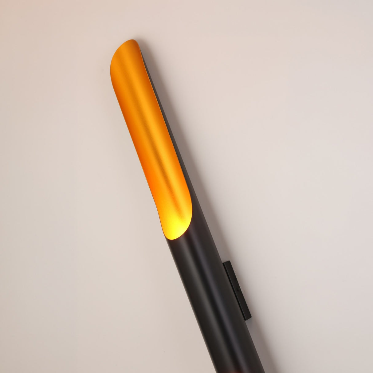 The Stealth 2 Light Wall Light features a modern brass and black cylindrical design with a rounded top, presented against a plain light background.