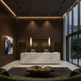 Modern lobby with a marble reception desk, two chairs, Aurelia LED Alabaster Pendant Light – Soft White, wood-paneled walls, large windows, abstract art, a round wooden coffee table, and a green curved sofa on a dark rug.