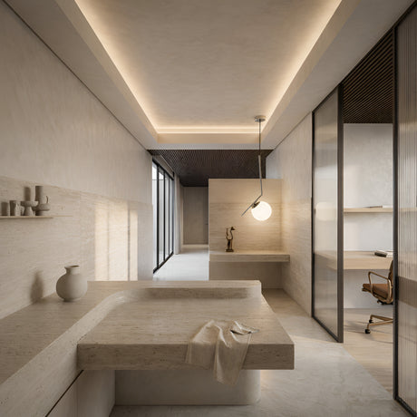 A modern minimalist bathroom with beige stone surfaces, a built-in sink, and a towel. The Vetra Opal Glass Large Pendant Light - Grey provides soft indirect light as a frosted glass wall separates it from the bright office area with desk and chair.
