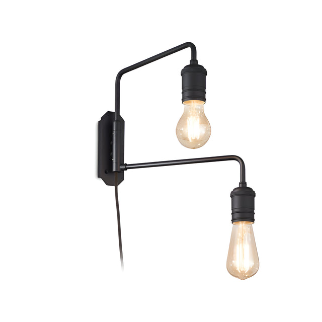 The Lustria 2 Light Wall Light - Black offers a vintage lighting charm with its modern black design featuring two exposed Edison bulbs on separate arms. Attached to a rectangular mount, this industrial wall light boasts a minimalist style and is plugged in with a visible black cord.