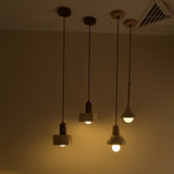 Lunaro Travertine & Walnut Single Pendant Light shown among four ceiling-hung pendants with cylindrical travertine shades, walnut caps, and E27 bulbs in a dimly lit room.