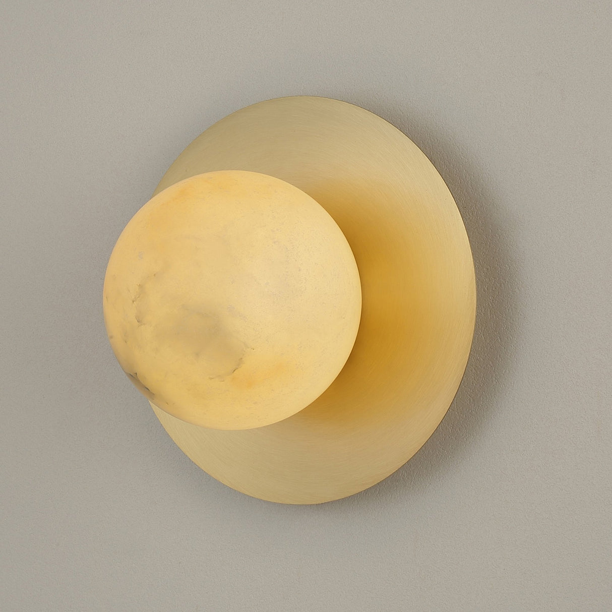 Niori Oria Alabaster Globe Wall Light in brushed brass, featuring a cream alabaster sphere with natural veining on a circular backplate.