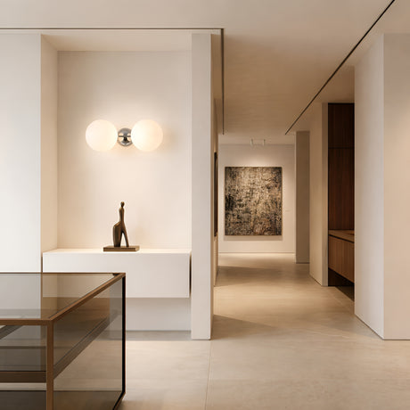 Modern minimalist hallway with neutral walls and floors, the Vetra 2 Light Opal Glass Wall/Semi-Flush Ceiling Light in grey, a sculptural figurine on a console, and a large abstract painting at the end of the hall.