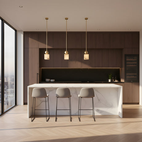A modern kitchen featuring a marble island, three gray barstools, dark wood cabinets, built-in appliances, large city-view windows, and the Serano 1 Light Medium Vertical Pillar Alabaster Single Pendant Light in Soft White & Brass.