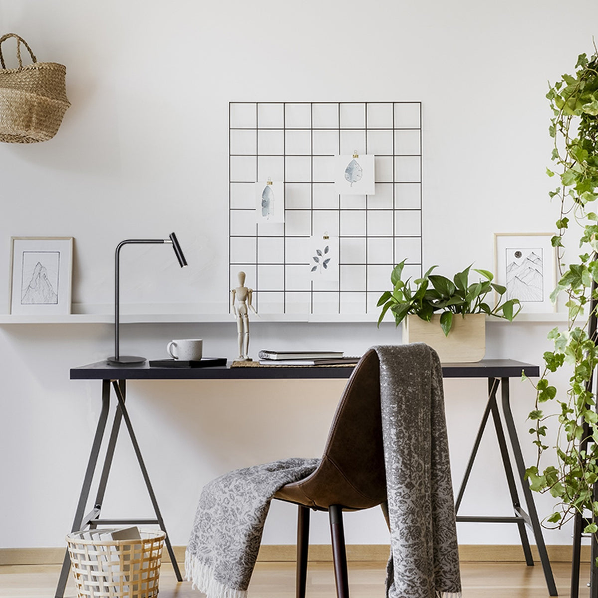 MiniSpot LED Table Lamp in black iron with round base and bent arm, shown on a home office desk beside a mug, notebook and decorative accessories.