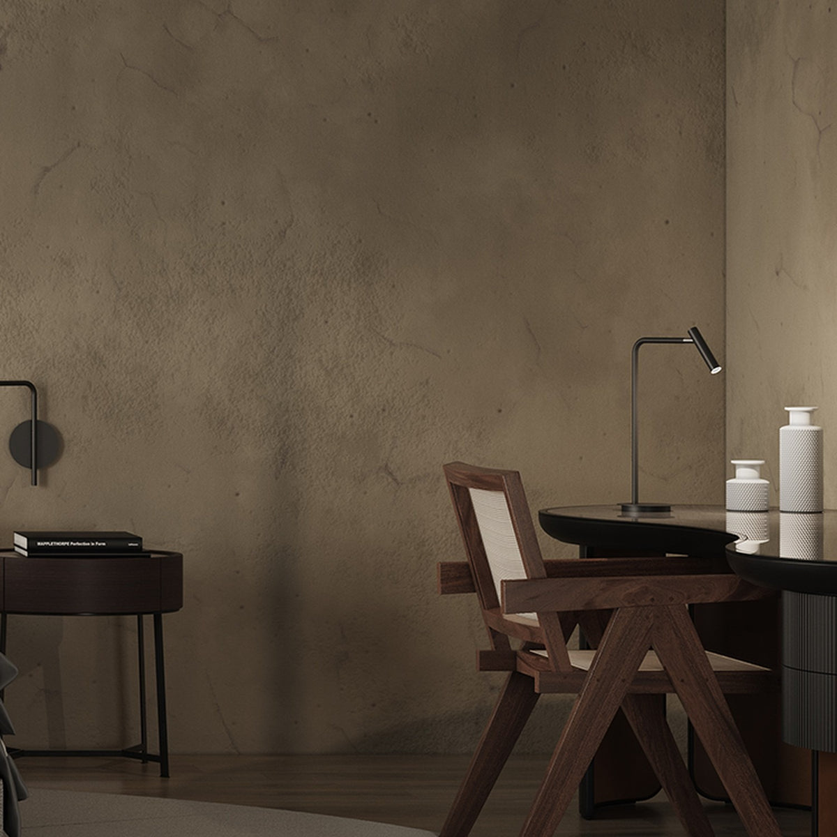 MiniSpot LED Table Lamp in black iron with round base and angled arm, shown on a desk beside a dark wood chair and table in a modern room.