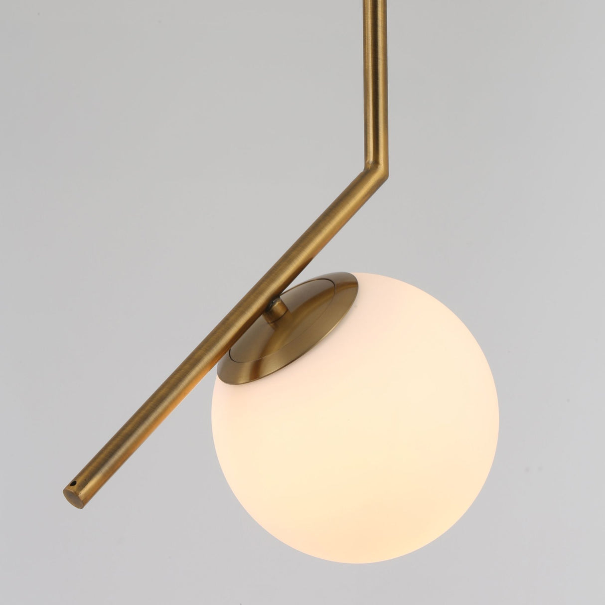 Niori Vetra Opal Glass Pendant Light in brushed gold, with an angled arm cradling a white opal glass globe against a light grey background.