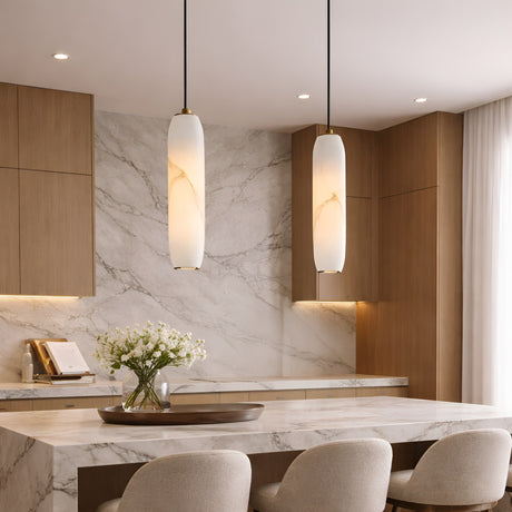 Modern kitchen with light wood cabinets, marble backsplash and countertops, Vireth 1 Light Small Cylinder Alabaster Single Pendant Lights in soft white, beige upholstered chairs, and a vase of white flowers on the island. Natural light comes through sheer curtains.