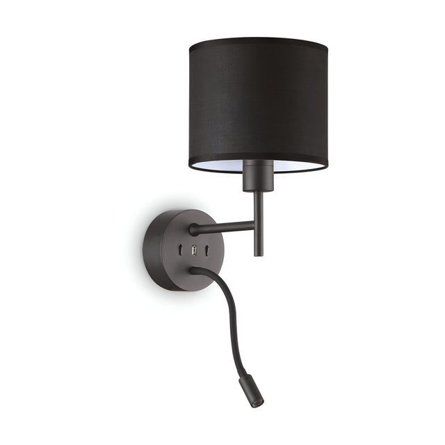 The Aethera Reading Wall Light - Black is a contemporary fixture featuring a black cylindrical shade and circular base. It boasts a sleek black metal finish and includes an additional flexible reading light along with an integrated USB port, making it ideal for modern interiors.