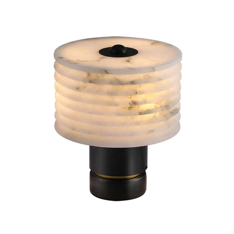 The Stravion 1 Light Small Ribbed Marble & Alabaster Table Lamp in soft white and black features a cylindrical ribbed marble shade with subtle gray veins on a short, round black metal base, emitting a warm, soft light.
