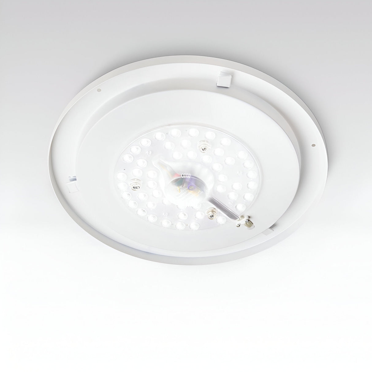 A close-up of the Mirage LED Ceiling & Wall Light 22.5W 3000K – White, 40cm showcases its energy-efficient illumination with multiple small bulbs arranged in a circular pattern. This versatile fixture seamlessly integrates with the flat white ceiling, combining modern design with functionality.