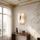 Elegant room with marble walls, gold-trimmed ceiling, and a Majorae LED Large Split Alabaster Wall Light—soft white with matte black—casting gentle light. A window shows a partial Eiffel Tower view. Books and a small statue sit on a wooden table.