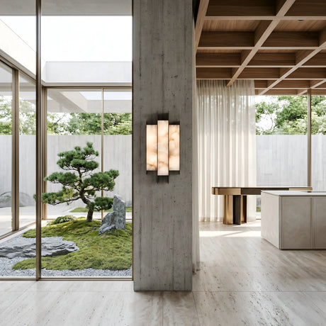 A modern interior with large windows showcases a minimalist indoor garden. Natural light illuminates the Tessaro LED Layered Panel Alabaster Wall Light in Soft White & Black, wood ceiling accents, and sleek furniture.