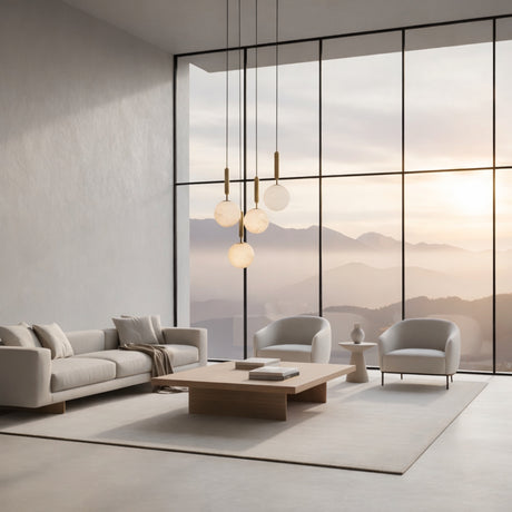 A modern, minimalist living room with neutral-toned furniture, a large wooden coffee table, the Lucentis 1 Light Globe Alabaster Single Pendant Light in soft white & brass, and floor-to-ceiling windows overlooking mountains at sunrise.