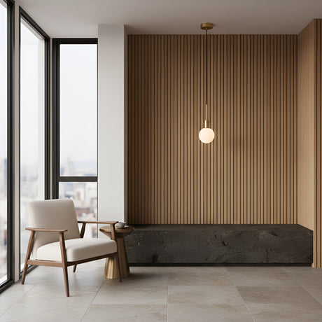 Minimalist room with large windows, a beige armchair, a small round gold side table, and the Astra 1 Light Alabaster Single Pendant Light in soft white & brushed brass. The back wall has vertical wooden slats and a dark built-in stone bench.