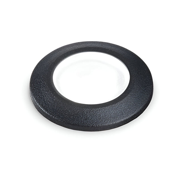 The Solarium Outdoor Drive Over Recessed Light 4000K in black, which appears as a circular object with a transparent center similar to a glass or lens encased in a black frame, is showcased on a white background. This light boasts an IP67 rating, guaranteeing its durability and protection against harsh outdoor conditions.