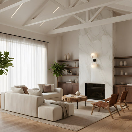 A modern living room with white walls, exposed beams, a marble fireplace, beige sofas, wooden chairs, potted plants, and built-in shelves is softly lit by the Althia LED Alabaster Wall Light – Matte Black & Soft White near sheer-curtained windows.