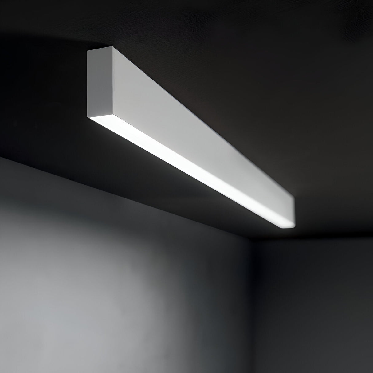 The Ignitia-2 LED Suspension Light 36W 4000K - White, a sleek rectangular fixture, is mounted on a dark ceiling, casting a soft glow throughout the space. Its energy-efficient design perfectly complements contemporary interiors with its minimalist charm.