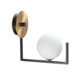 The Ethereal Wall Light - White showcases a minimalist design with its circular brass backplate and geometric black metal frame. Its white spherical light fixture adds an elegant touch, making a refined statement in any interior lighting setting.