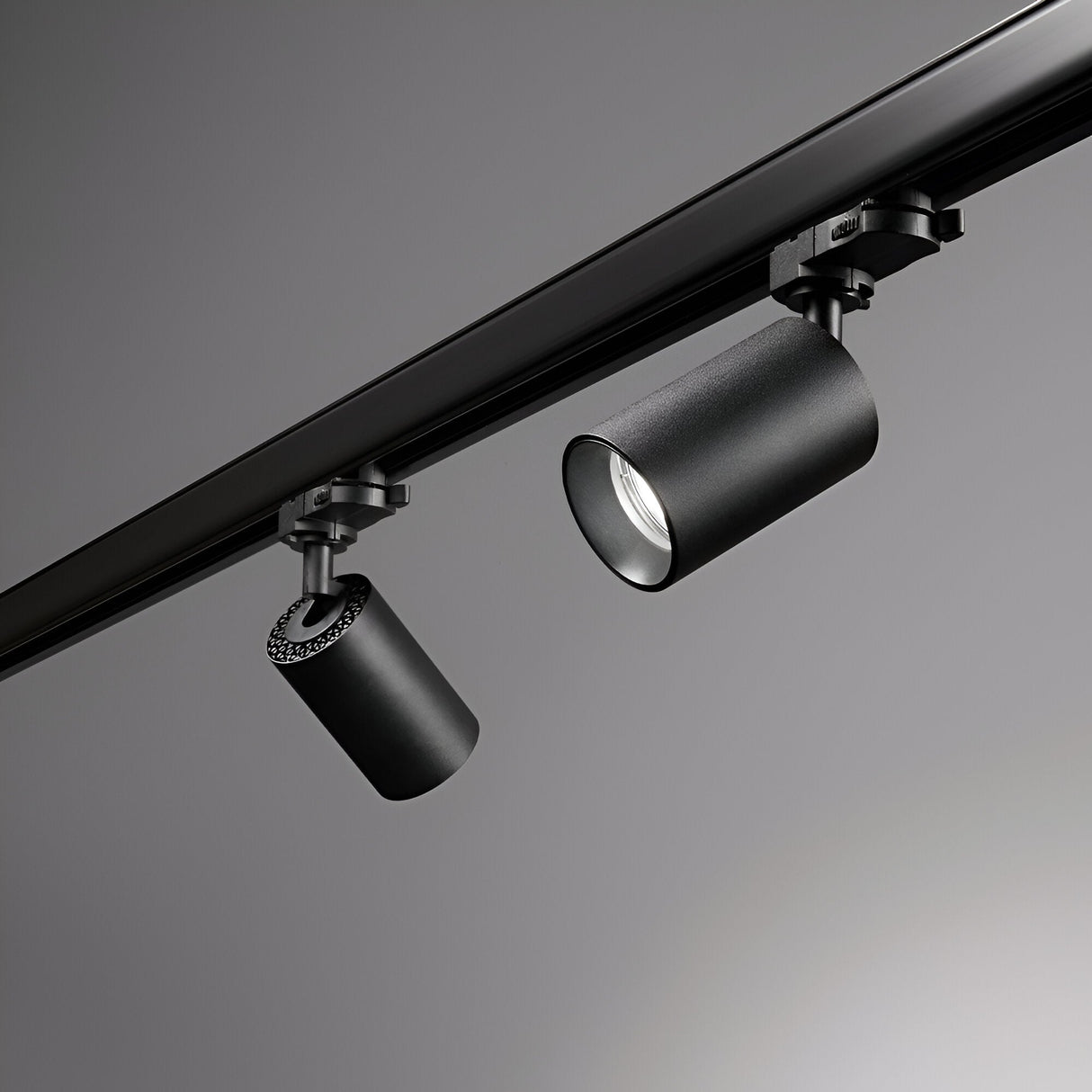 A detailed view of the Glimmera Three Phase Track Spotlight in black, showcasing its dual cylindrical fixtures with adjustable heads on a sleek track against a gray backdrop. The modern, minimalist design of these lights is complemented by a dimmable feature for versatile ambiance control.