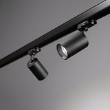 A detailed view of the Glimmera Three Phase Track Spotlight in black, showcasing its dual cylindrical fixtures with adjustable heads on a sleek track against a gray backdrop. The modern, minimalist design of these lights is complemented by a dimmable feature for versatile ambiance control.