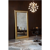 Nick Gold Leaf Full Length Mirror, 189cm rectangular wall mirror with a faceted gold-leaf frame, shown leaning against a dark wood-panelled wall in a living room setting.