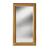 Full length rectangular mirror in a wide surround of gold leaf pyramids, each facet cut to catch the light, on a plain background.