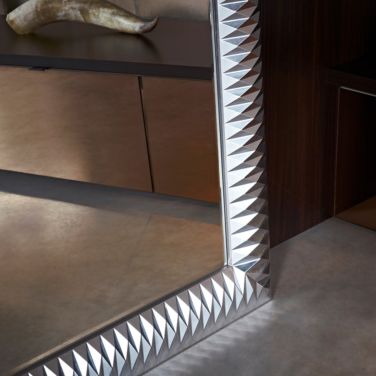 Nick Silver Leaf full length wall mirror, corner detail showing faceted silver leaf frame with pyramid-fold texture, reflecting a room with dark cabinetry.