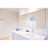 Lucka Gold Framed Full Length Mirror mounted above a bathroom double vanity, its slim gold metal rectangular frame and clear glass reflecting an arched window.
