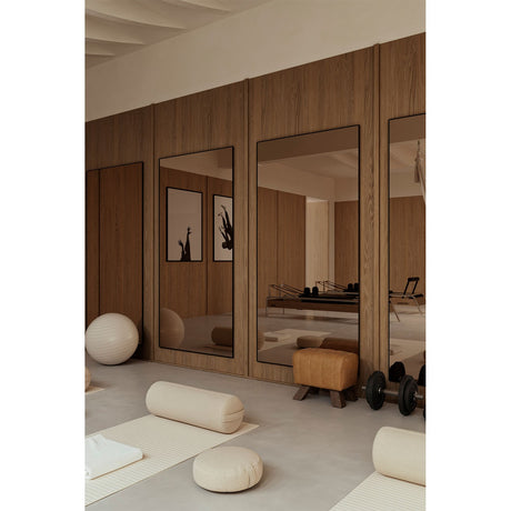 Lucka Bronze Tinted Full Length Mirror 200cm in a black metal frame, mounted in a wood-panelled studio between wall panels, reflecting gym equipment and floor cushions.