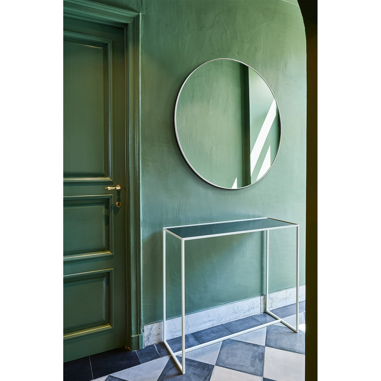 Mesa White console table with slim white metal frame and mirrored glass top, styled beneath a round mirror in a green-walled hallway.
